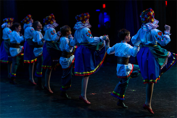 Edmonton School of Ukrainian Dance talented dancers on stage holding hands.